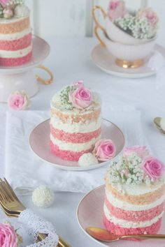 three layered cake with pink and white frosting sitting on plates next to each other