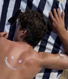 a man laying on top of a towel covered in sunscreen