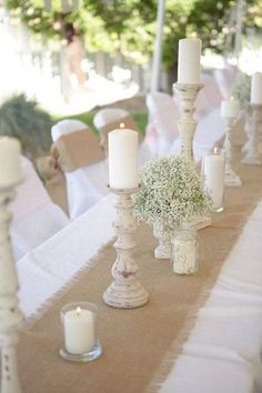 the table is set up with candles and baby's breath centerpieces on it