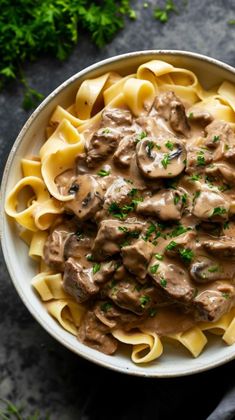 a bowl filled with pasta covered in mushroom sauce and garnished with parsley