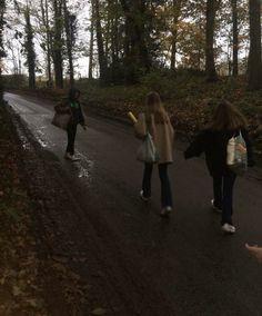 three people walking down the road in the woods