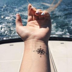 a person's arm with a compass tattoo on it, and the water in the background