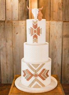 a three tiered wedding cake with an arrow decoration