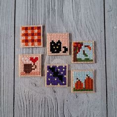 six cross stitch squares with cats and pumpkins in them on a wooden table top