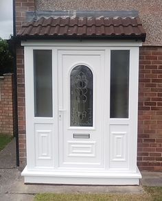 a white door with glass on the side of a brick building next to a sidewalk