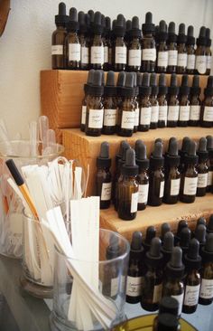 many bottles and spoons are sitting on a shelf next to each other in front of the wall