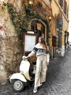 a woman standing next to a scooter in front of a building