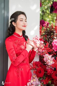 a woman in a red dress standing next to flowers