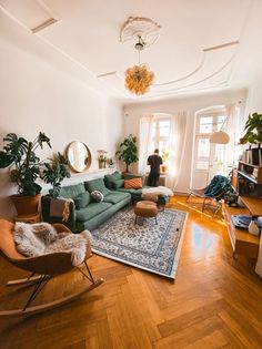 a living room filled with lots of furniture and plants on top of a hard wood floor