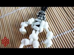 a necklace with white beads and a skull on it sitting on top of a bamboo mat