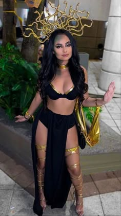 a woman in a black and gold costume posing for the camera with her hands out