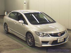 a silver car parked in a garage next to a white wall and green lines on the ground