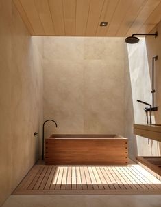 a bathroom with a wooden floor and bathtub next to a shower head mounted on the wall