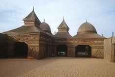 an old building made out of mud and straw with two cars parked in the doorway