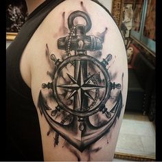 a man's arm with an anchor, compass and ship wheel tattoo on it