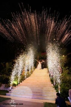 the bride and groom are walking down the stairs with fireworks