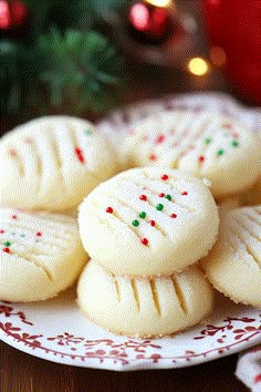 some cookies are sitting on a plate next to a christmas tree