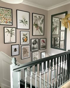 there are many framed pictures on the wall next to the bannister and stairs