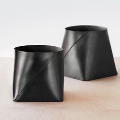 two black vases sitting on top of a wooden table