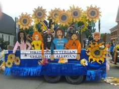 the float is decorated with sunflowers and people on it's sides,