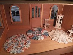 a doll house with furniture and crocheted rugs