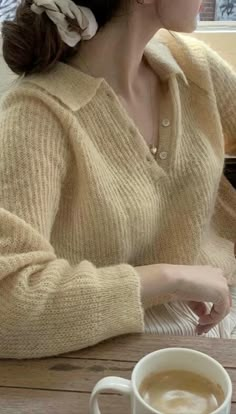 a woman sitting at a table with a cup of coffee