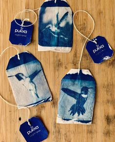 four tags with blue and white designs on them sitting on a wooden table next to each other