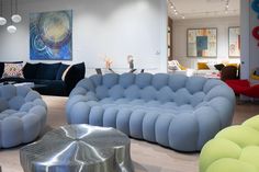 a living room filled with lots of different colored couches and chairs on top of hard wood flooring