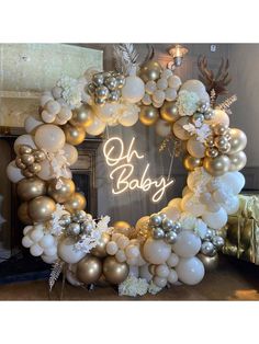 a balloon wreath with the words oh baby written in white and gold balloons on it