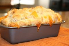 a casserole dish with meat and cheese on it sitting on a wooden table