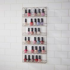 a metal shelf with several different nail polish bottles hanging on it's sides in front of a white tiled wall