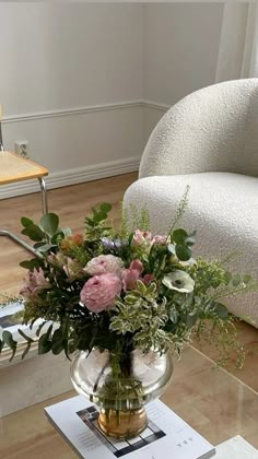 a vase filled with flowers sitting on top of a glass table next to a chair