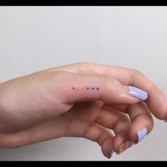 a woman's left hand with small dots painted on the tip of her finger