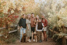 a group of people standing next to each other on a dirt road near trees and bushes