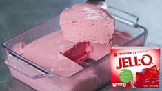 a pink jello in a plastic container next to a carton of jello