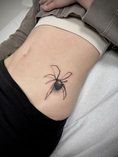 a woman's stomach with a spider tattoo on it