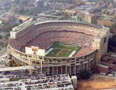 an aerial view of a football stadium with cars parked in the parking lot and lots of people