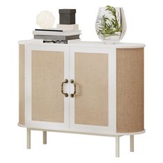 a white cabinet with two doors and some books on top of it next to a glass vase