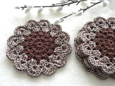 two crocheted coasters sitting next to each other on a white tablecloth