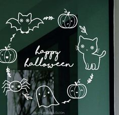 a window with halloween stickers on it in front of a green wall and black door