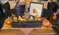 an arrangement of pumpkins and gourds on a coffee table in a living room