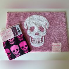 a pink rug with a skull on it next to a wallet and other items in front of it