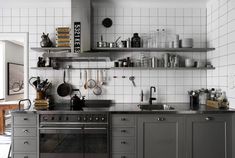 a kitchen with stainless steel appliances and open shelving on the wall above the stove