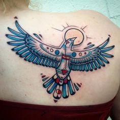 the back of a woman's shoulder with an egyptian bird tattoo on her upper arm