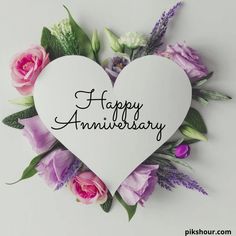 a white heart with the words happy anniversary written on it surrounded by pink and purple flowers