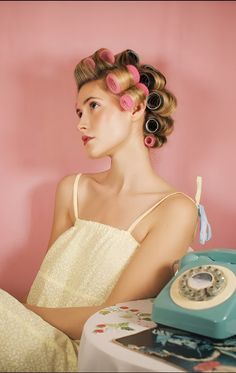 a woman sitting at a table with an old fashioned telephone on it's side