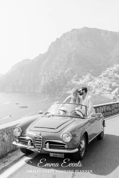 a bride and groom kissing in the back of a convertible car by the sea on their wedding day