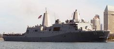 a large gray ship floating on top of a body of water next to tall buildings