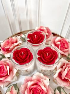 four candles with red roses in them on a plate