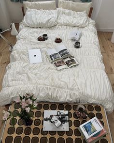 a bed with white sheets and pillows on top of it next to a coffee table